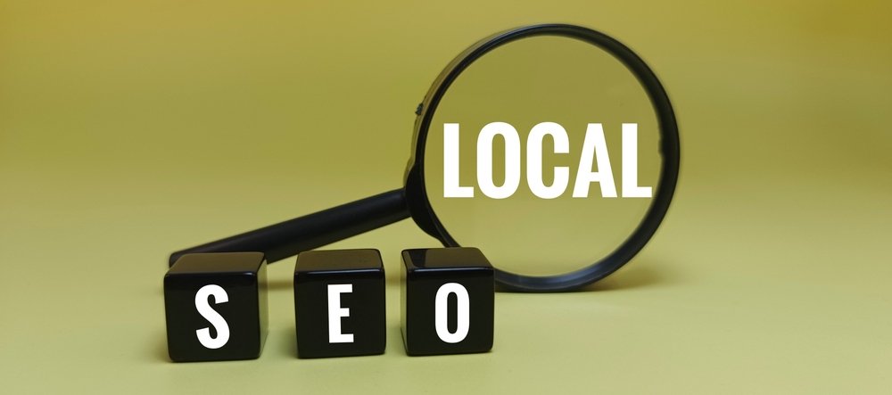 Local SEO concept featuring a magnifying glass highlighting the word LOCAL above SEO letter blocks, representing local search optimization and business visibility in search results.