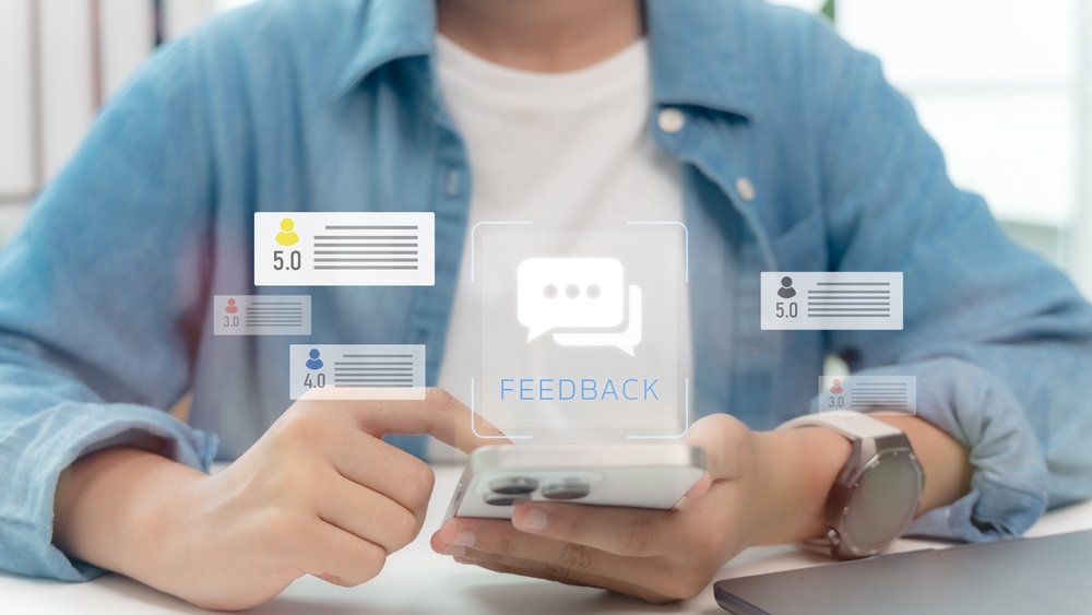 Person using a smartphone with feedback icons and star rating reviews displayed, representing online reputation management.